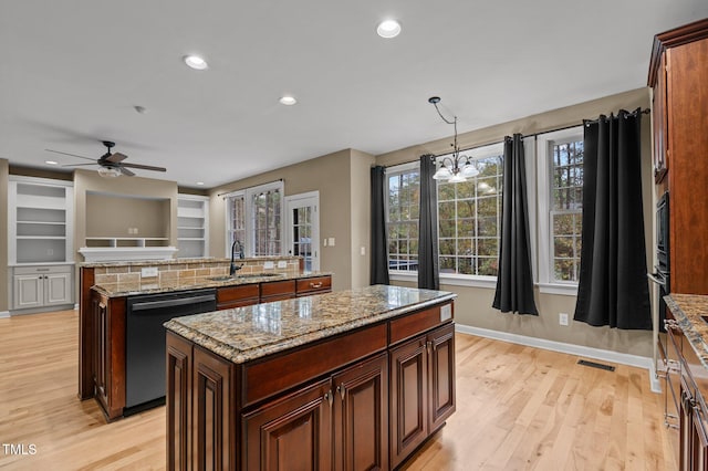 kitchen with light stone counters, dishwashing machine, sink, a center island, and hanging light fixtures