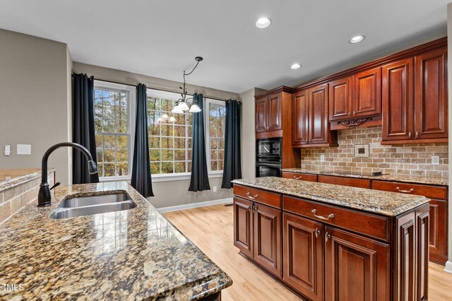 5600 Thornburg Dr, Wake Forest, NC 27587 - kitchen featuring a sink, black appliances, light wood-style floors, backsplash, and pendant lighting