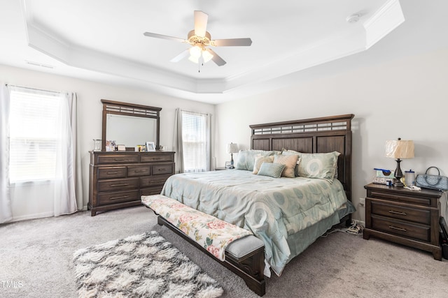 carpeted bedroom featuring ceiling fan, a raised ceiling, and ornamental molding