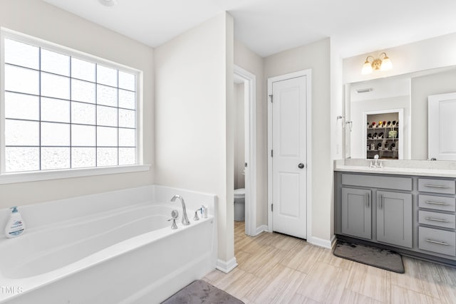 bathroom with vanity, a tub to relax in, and toilet