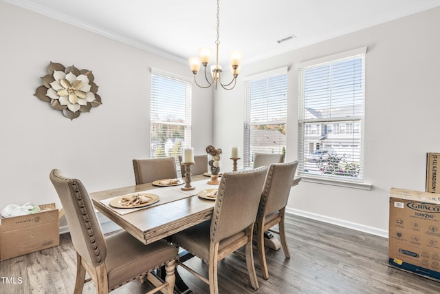 dining area featuring a wealth of natural light, hardwood / wood-style floors, a notable chandelier, and crown molding