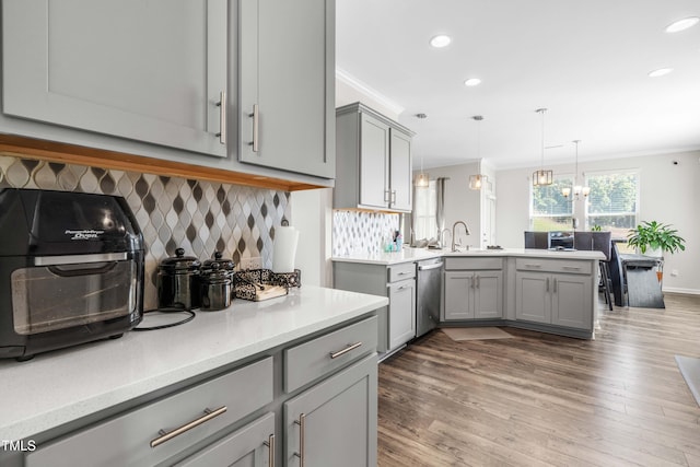 kitchen with hardwood / wood-style flooring, decorative light fixtures, stainless steel dishwasher, crown molding, and gray cabinetry