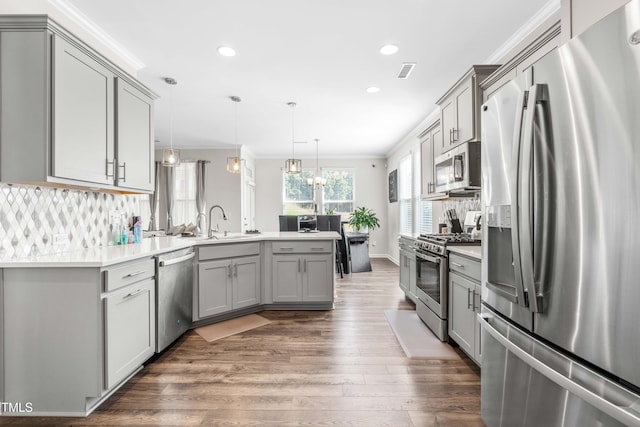 kitchen featuring appliances with stainless steel finishes, backsplash, decorative light fixtures, gray cabinets, and dark hardwood / wood-style flooring