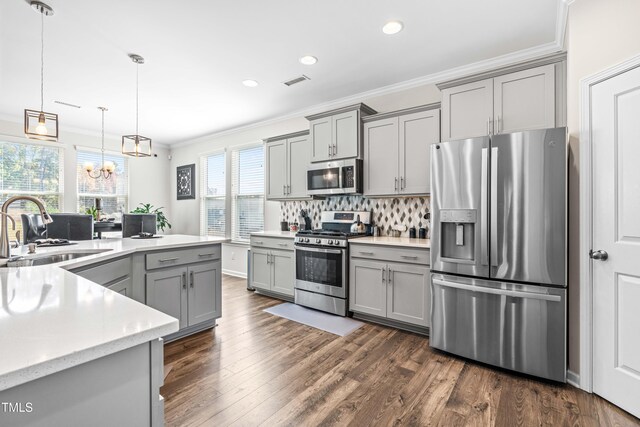 kitchen featuring stainless steel appliances, sink, hanging light fixtures, dark wood-type flooring, and gray cabinetry