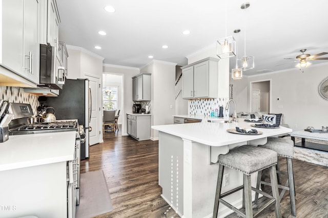 kitchen featuring stainless steel appliances, a breakfast bar area, decorative light fixtures, dark wood-type flooring, and gray cabinets