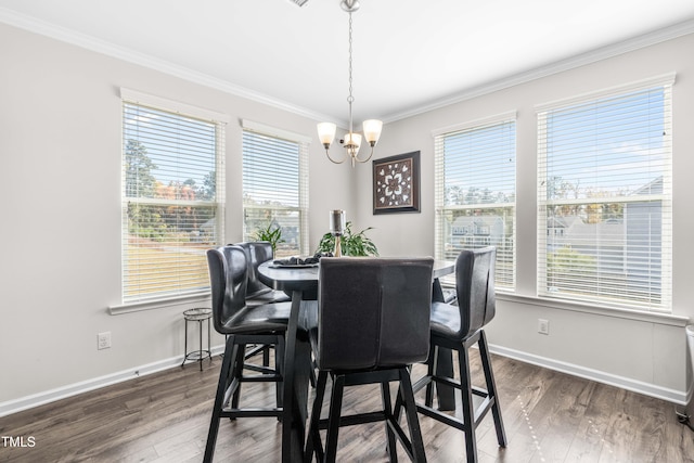 dining area featuring dark wood-type flooring, crown molding, and a notable chandelier