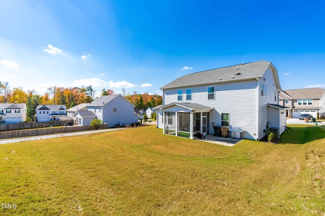 rear view of property with a lawn, a patio, and a sunroom