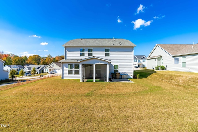 rear view of house featuring a lawn, a sunroom, and a patio area