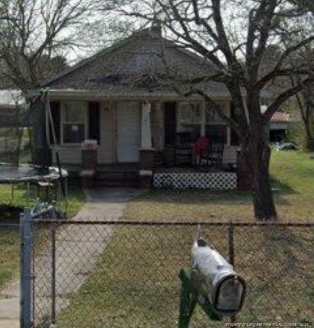 bungalow-style home with a front lawn and a trampoline