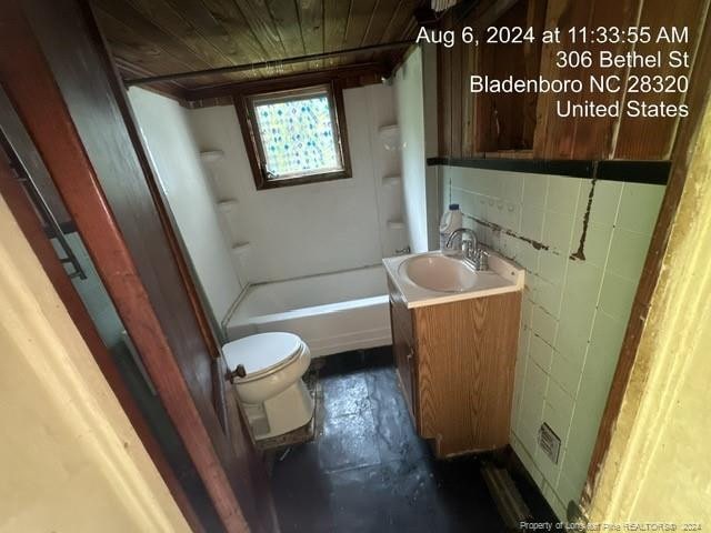 bathroom with concrete flooring, vanity, toilet, and wooden ceiling