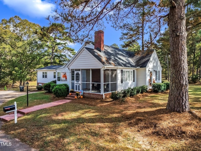 view of front of house featuring a sunroom and a front lawn