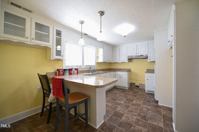 kitchen featuring white cabinetry, pendant lighting, sink, a breakfast bar, and kitchen peninsula