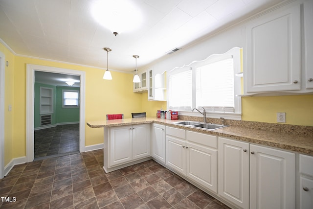 kitchen with pendant lighting, kitchen peninsula, sink, and white cabinets