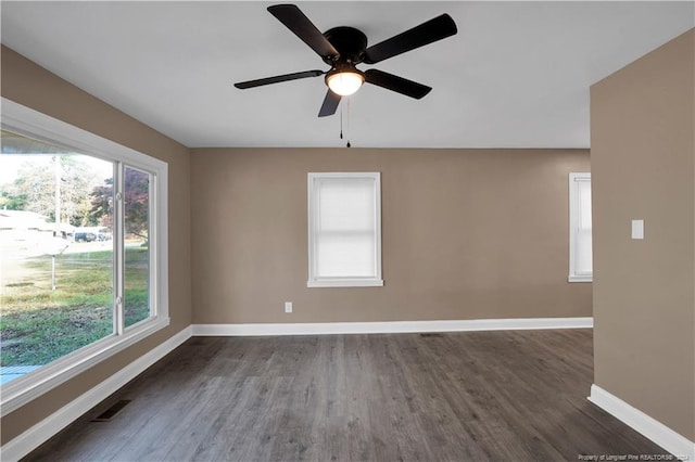 unfurnished room featuring a wealth of natural light, ceiling fan, and dark hardwood / wood-style flooring