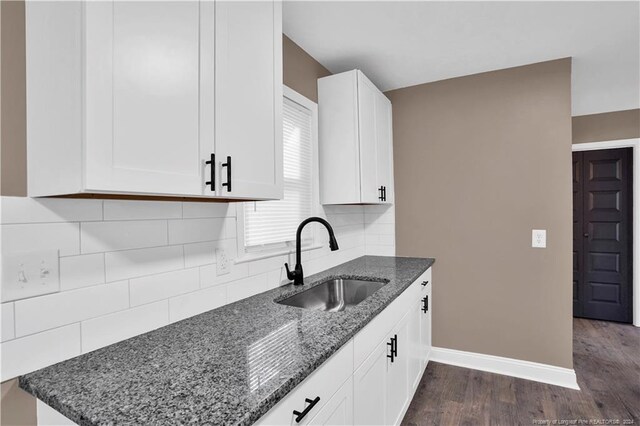 kitchen with tasteful backsplash, white cabinetry, sink, dark wood-type flooring, and dark stone countertops