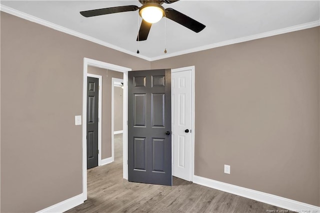 unfurnished bedroom featuring light wood-type flooring, ceiling fan, and crown molding