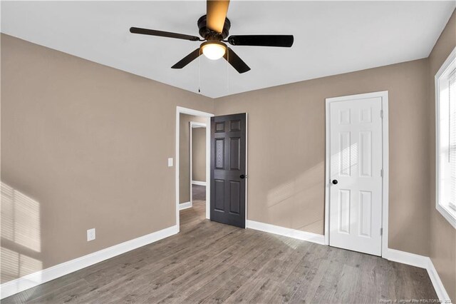 unfurnished bedroom with ceiling fan, multiple windows, and wood-type flooring