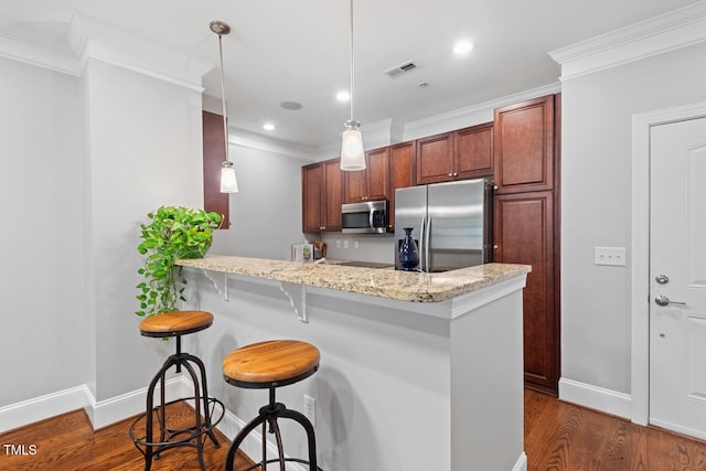 kitchen featuring appliances with stainless steel finishes, light stone countertops, hanging light fixtures, a kitchen breakfast bar, and dark wood-type flooring