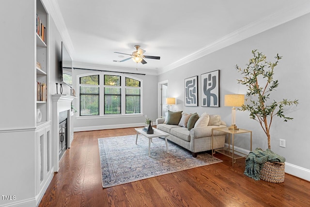 living room featuring a ceiling fan, crown molding, wood finished floors, baseboards, and a fireplace