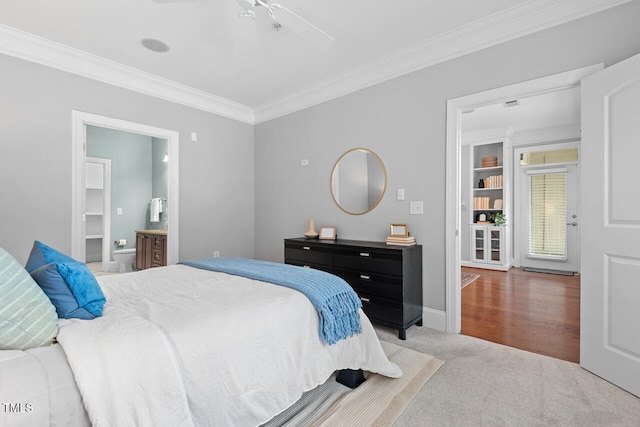 carpeted bedroom featuring ceiling fan, ensuite bath, and ornamental molding