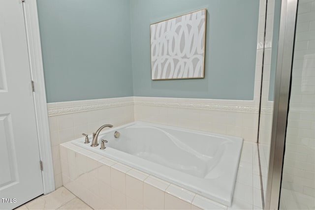 bathroom with tile patterned floors and a relaxing tiled tub