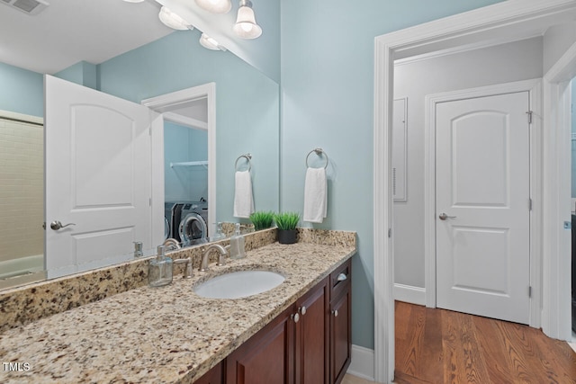 bathroom with hardwood / wood-style floors, vanity, and independent washer and dryer