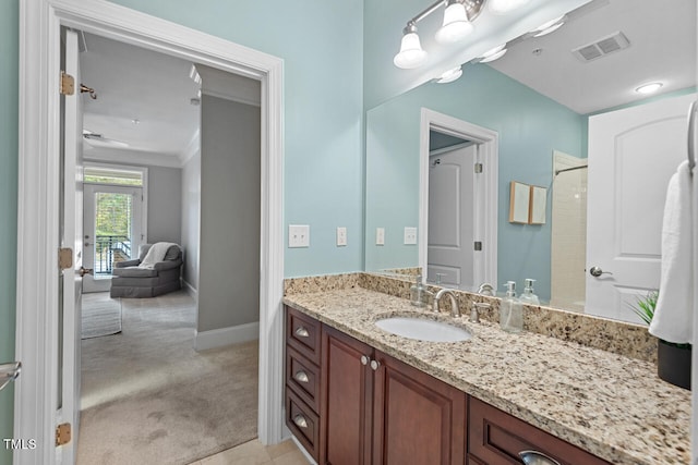 bathroom with ornamental molding, vanity, and a shower