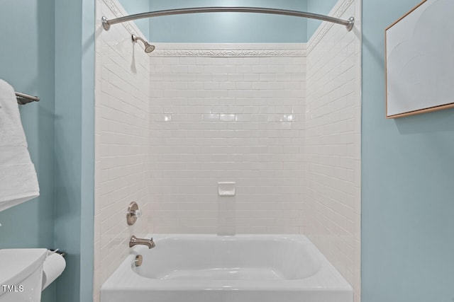 bathroom featuring tiled shower / bath combo and toilet