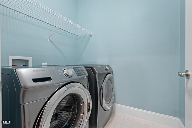 clothes washing area with independent washer and dryer, baseboards, and tile patterned floors