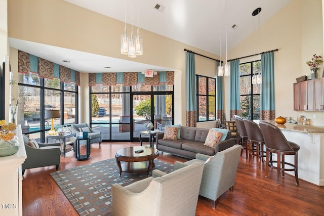 living room with wood finished floors, high vaulted ceiling, and a chandelier