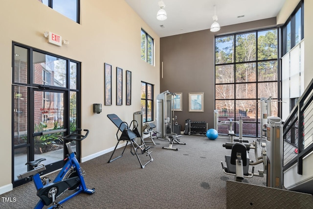 gym featuring a towering ceiling and carpet flooring