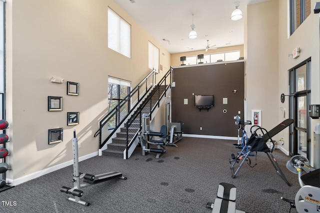 gym featuring a towering ceiling and a healthy amount of sunlight