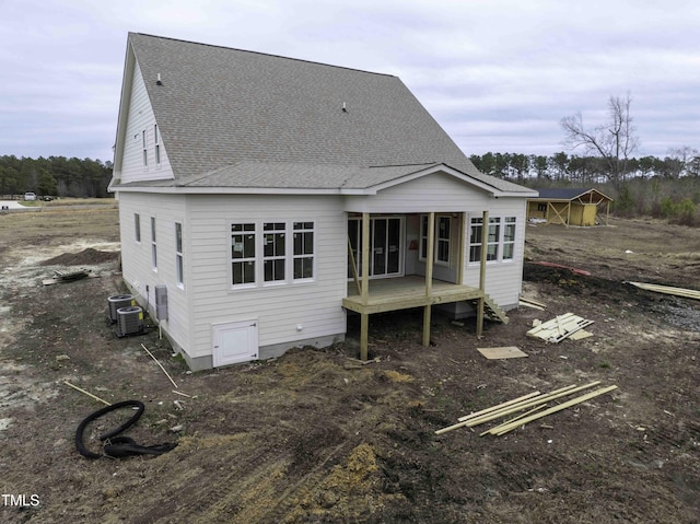 back of property featuring a shingled roof and central AC unit