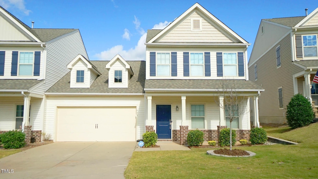 view of front of house featuring covered porch, a garage, and a front lawn