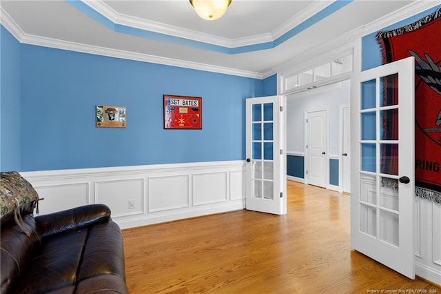 living area with french doors, hardwood / wood-style flooring, ornamental molding, and a raised ceiling