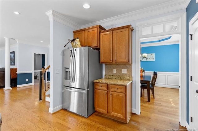 kitchen with stainless steel refrigerator with ice dispenser, light stone countertops, light wood-type flooring, and ornamental molding