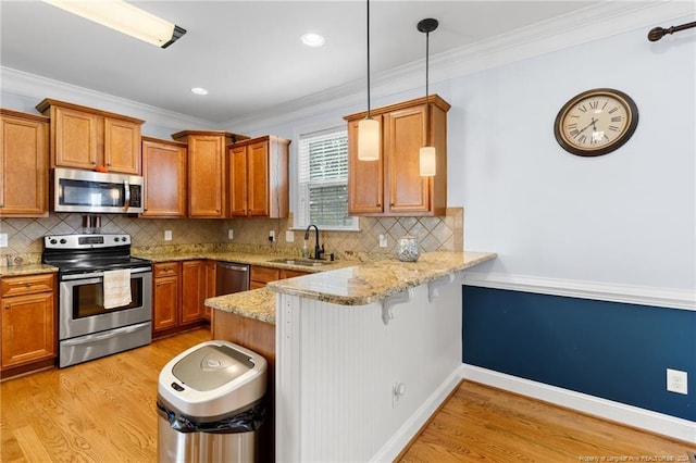 kitchen with stainless steel appliances, a breakfast bar area, hanging light fixtures, light hardwood / wood-style flooring, and crown molding