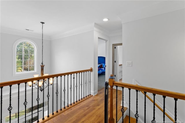 hallway featuring wood-type flooring, crown molding, and a notable chandelier