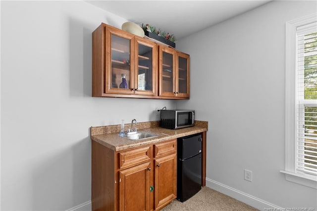 bar featuring black fridge, light carpet, and sink