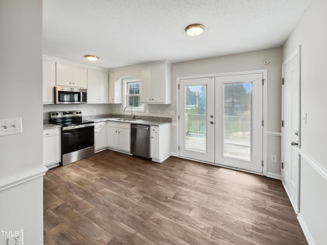 kitchen featuring sink, appliances with stainless steel finishes, dark hardwood / wood-style floors, white cabinets, and french doors