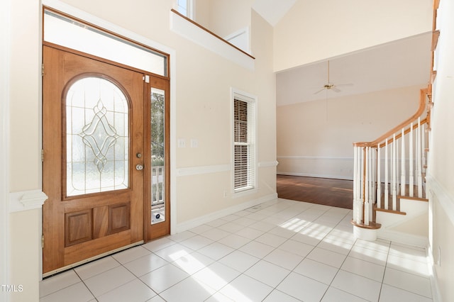 foyer entrance featuring light tile patterned floors, high vaulted ceiling, and ceiling fan