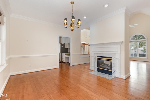 unfurnished living room with light hardwood / wood-style flooring, a high end fireplace, an inviting chandelier, and ornamental molding