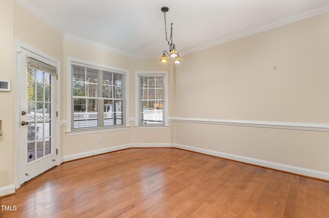 unfurnished dining area with light hardwood / wood-style floors, crown molding, a wealth of natural light, and a chandelier