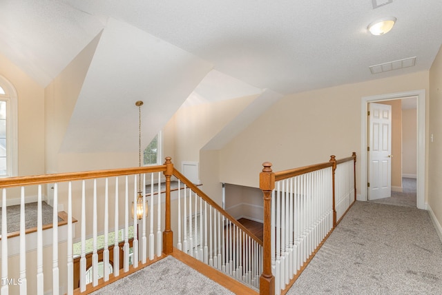 corridor with carpet flooring, lofted ceiling, a textured ceiling, and a wealth of natural light