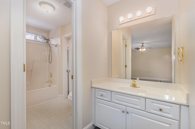 full bathroom with ceiling fan, a textured ceiling,  shower combination, toilet, and vanity