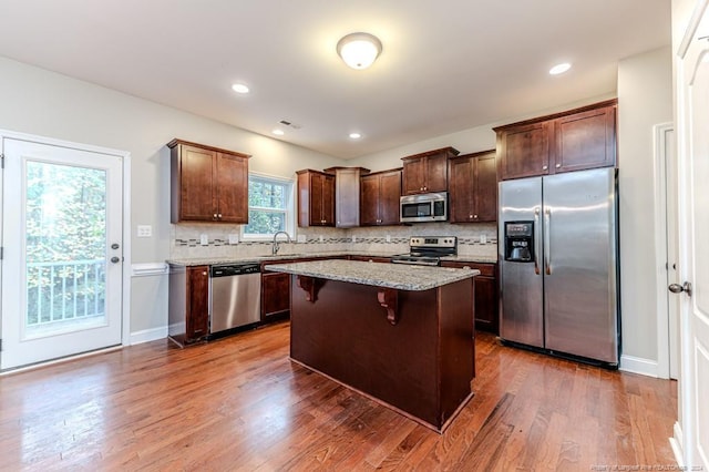 kitchen with appliances with stainless steel finishes, dark wood-type flooring, sink, and a center island