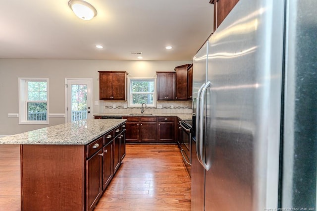 kitchen with light hardwood / wood-style floors, a healthy amount of sunlight, a kitchen island, and stainless steel fridge with ice dispenser