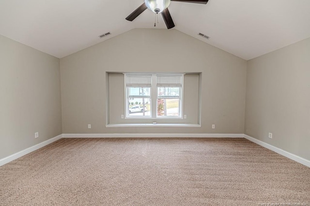 carpeted spare room featuring vaulted ceiling and ceiling fan