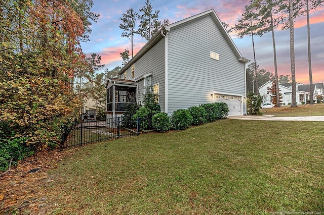 property exterior at dusk featuring a garage, a sunroom, and a yard