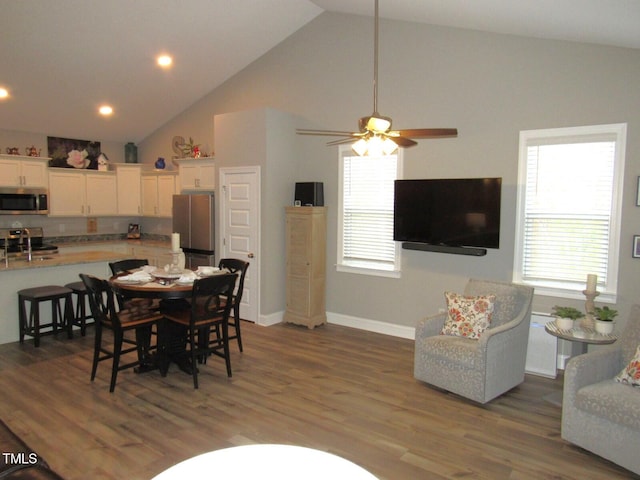 dining area featuring ceiling fan, a wealth of natural light, dark hardwood / wood-style floors, and high vaulted ceiling